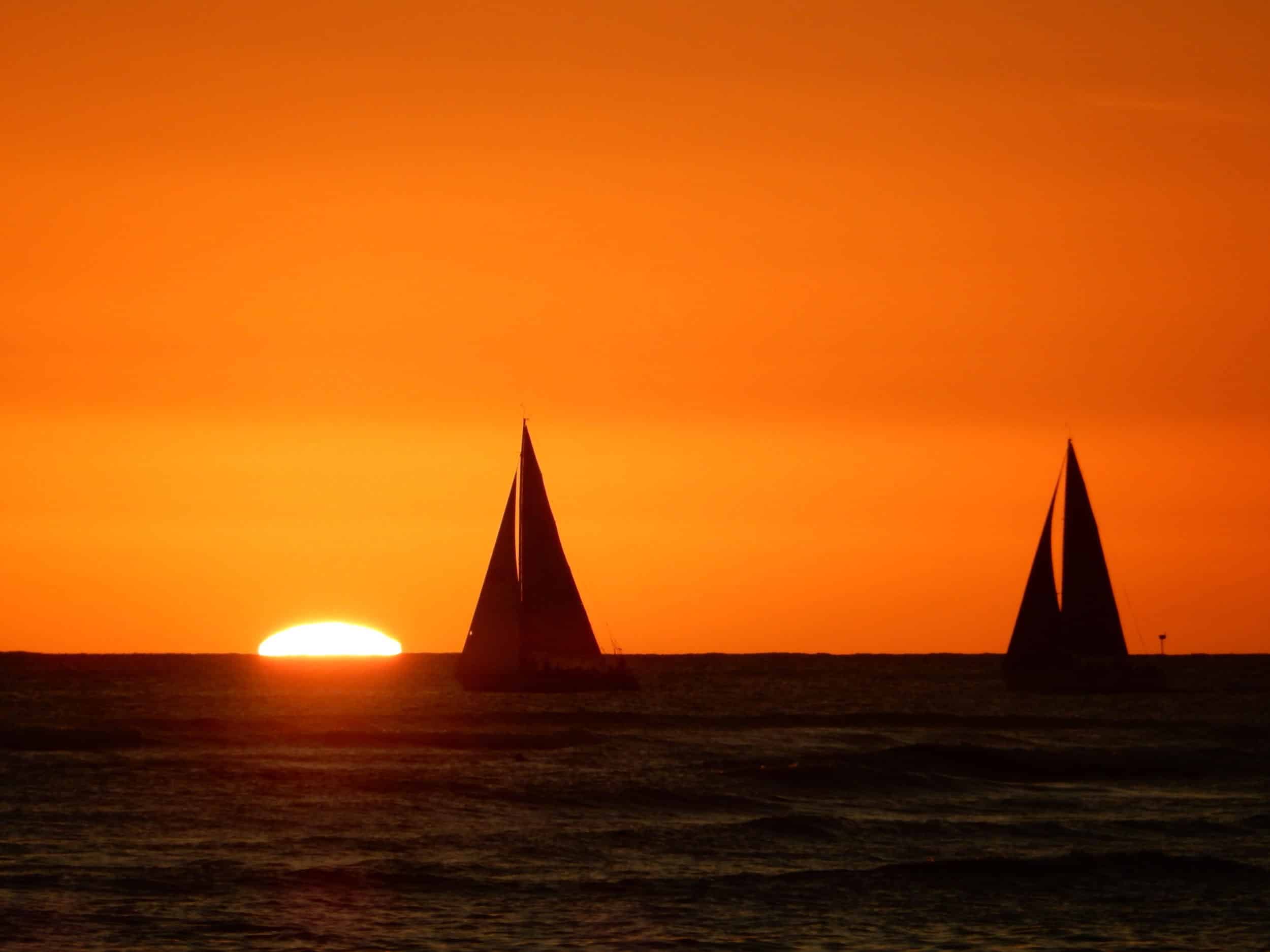 Oahu orange Sunset with sailboat Silhouettes